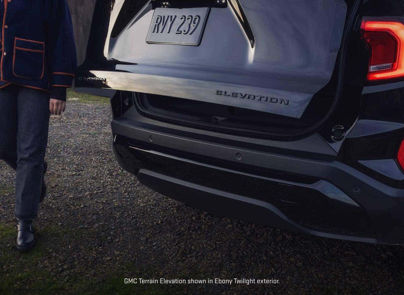 Close-up rear view of a 2027 GMC Terrain Elevation in Ebony Twilight Metallic, showing the opening tailgate with ELEVATION badging.