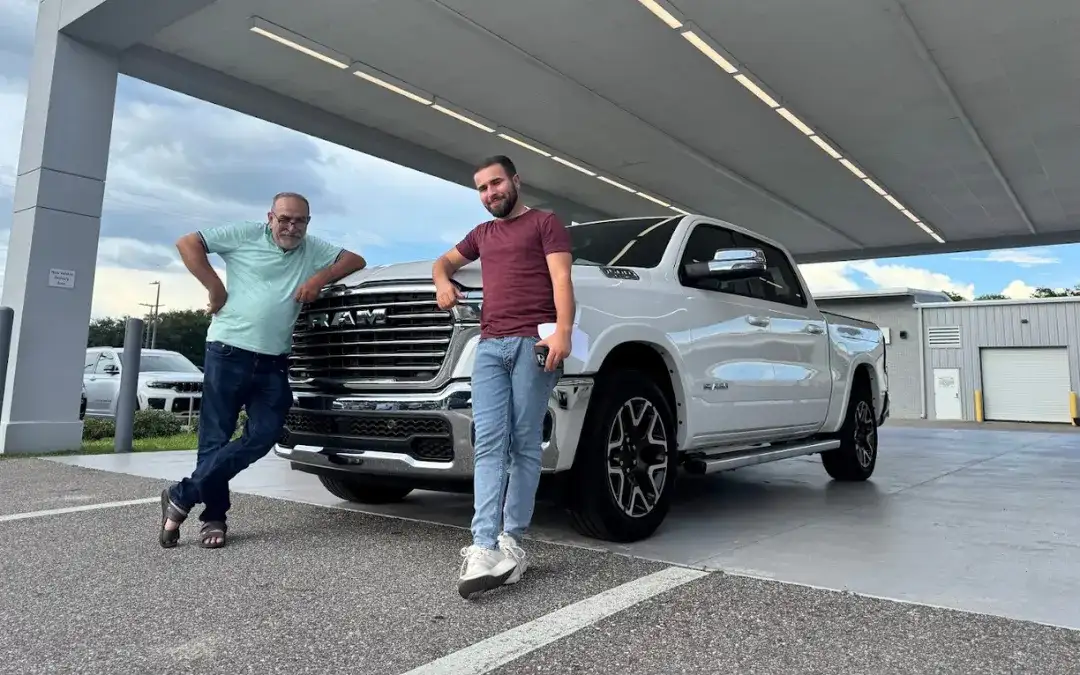 Two customers standing in front of white RAM truck outside of Jim Browne CDJR