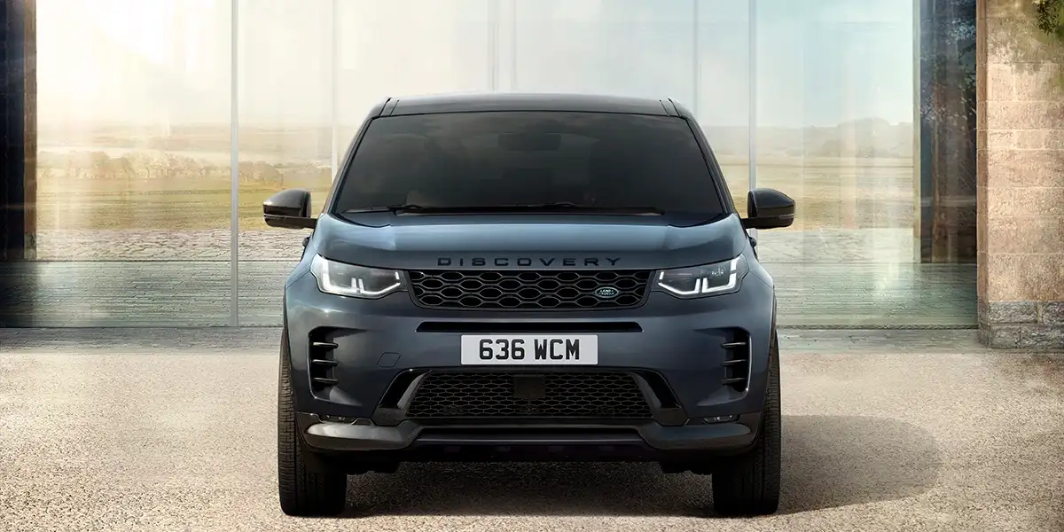 2026 Land Rover Discovery Sport Dynamic HSE front view in urban setting with modern SUV styling.