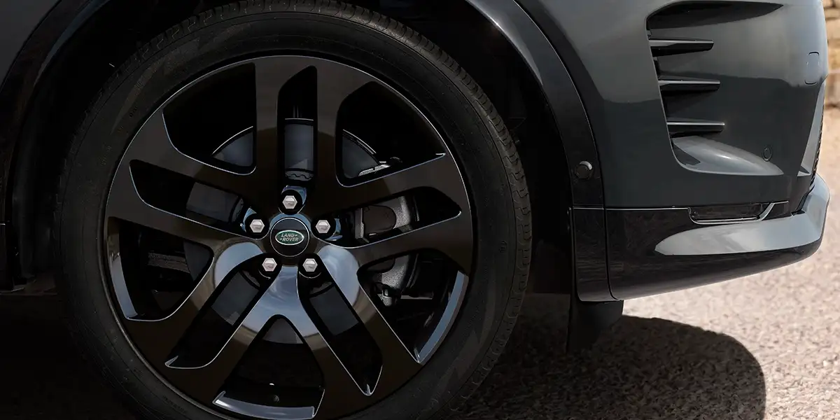 Gloss black alloy wheel of 2026 Land Rover Discovery Sport Dynamic HSE with Land Rover badge.