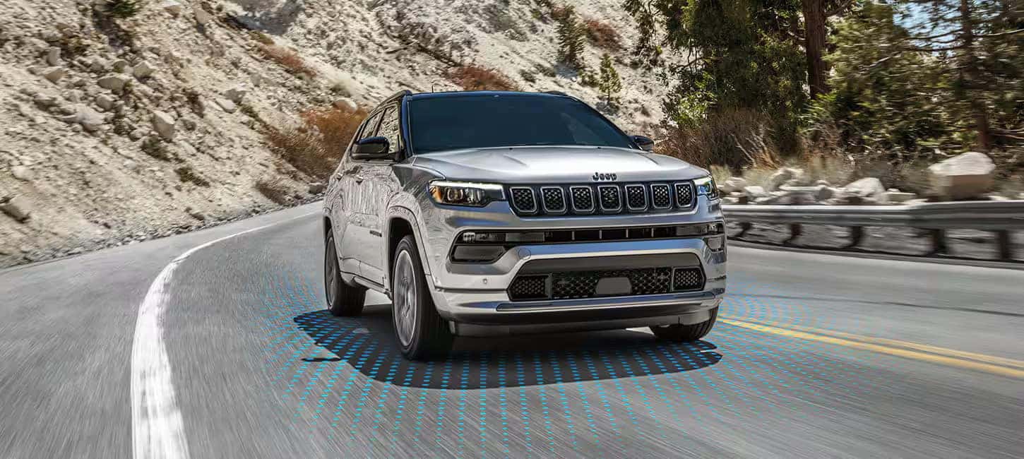2024 Jeep Compass driving on a winding road, demonstrating lane-keeping assist and safety features