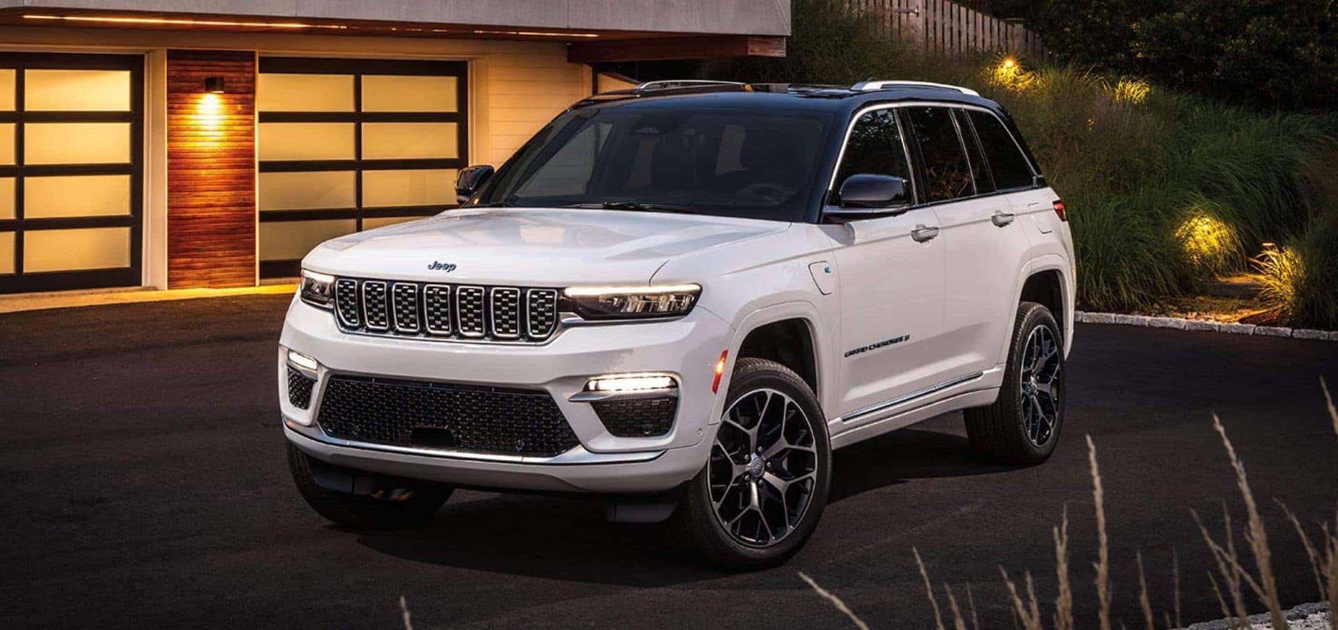 2025 Jeep Grand Cherokee parked outside a modern home, highlighting its elegant design and LED headlights.