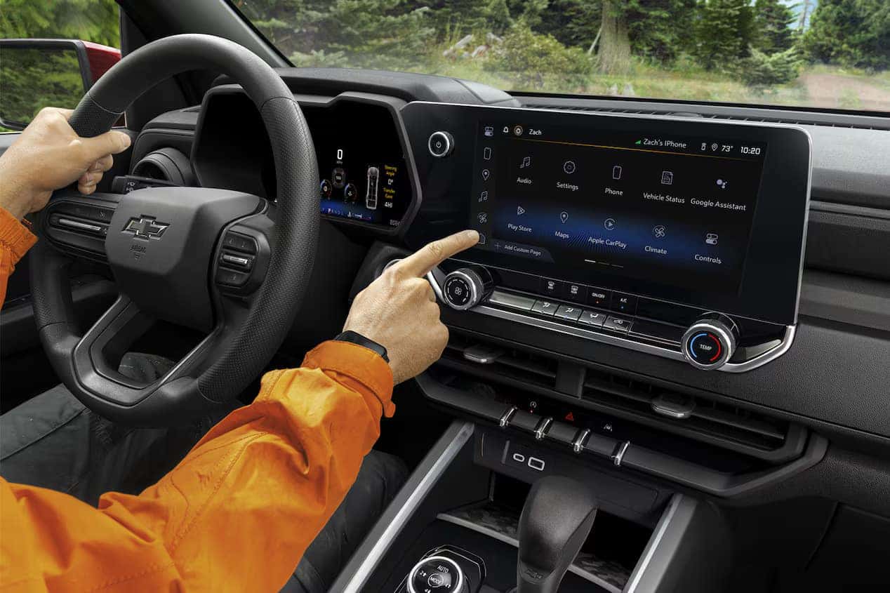2024 Chevrolet Colorado interior featuring the driver interacting with the vehicle's modern infotainment system.