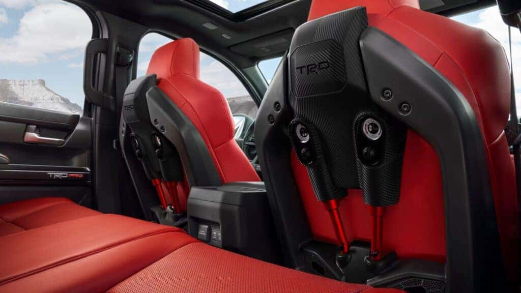 Interior view of the 2024 Toyota Tacoma TRD Pro with red seats and carbon-fiber accents, showcasing premium off-road style.
