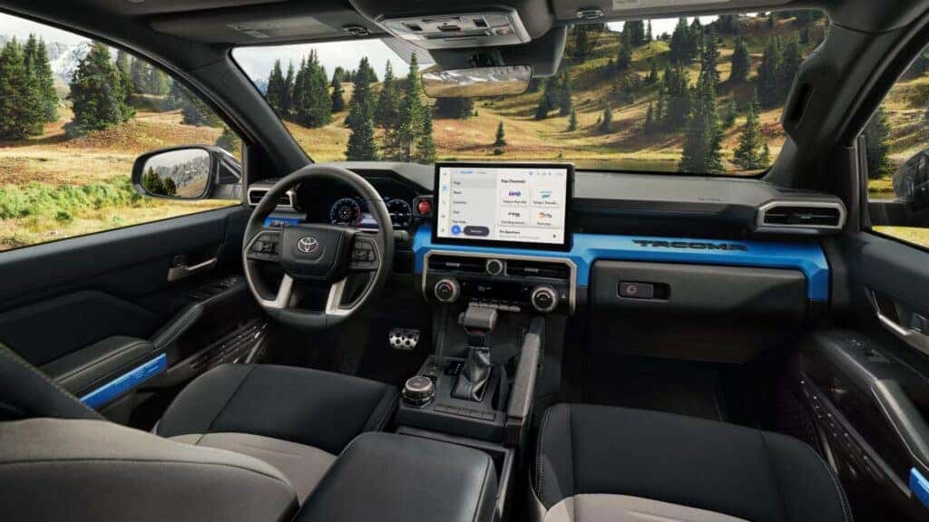 Interior of the Toyota Tacoma cabin featuring a sleek dashboard with a large touchscreen display and scenic views outside.