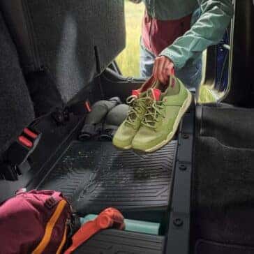 Interior storage of a Toyota Tacoma with under-seat storage space featuring shoes and camping gear.