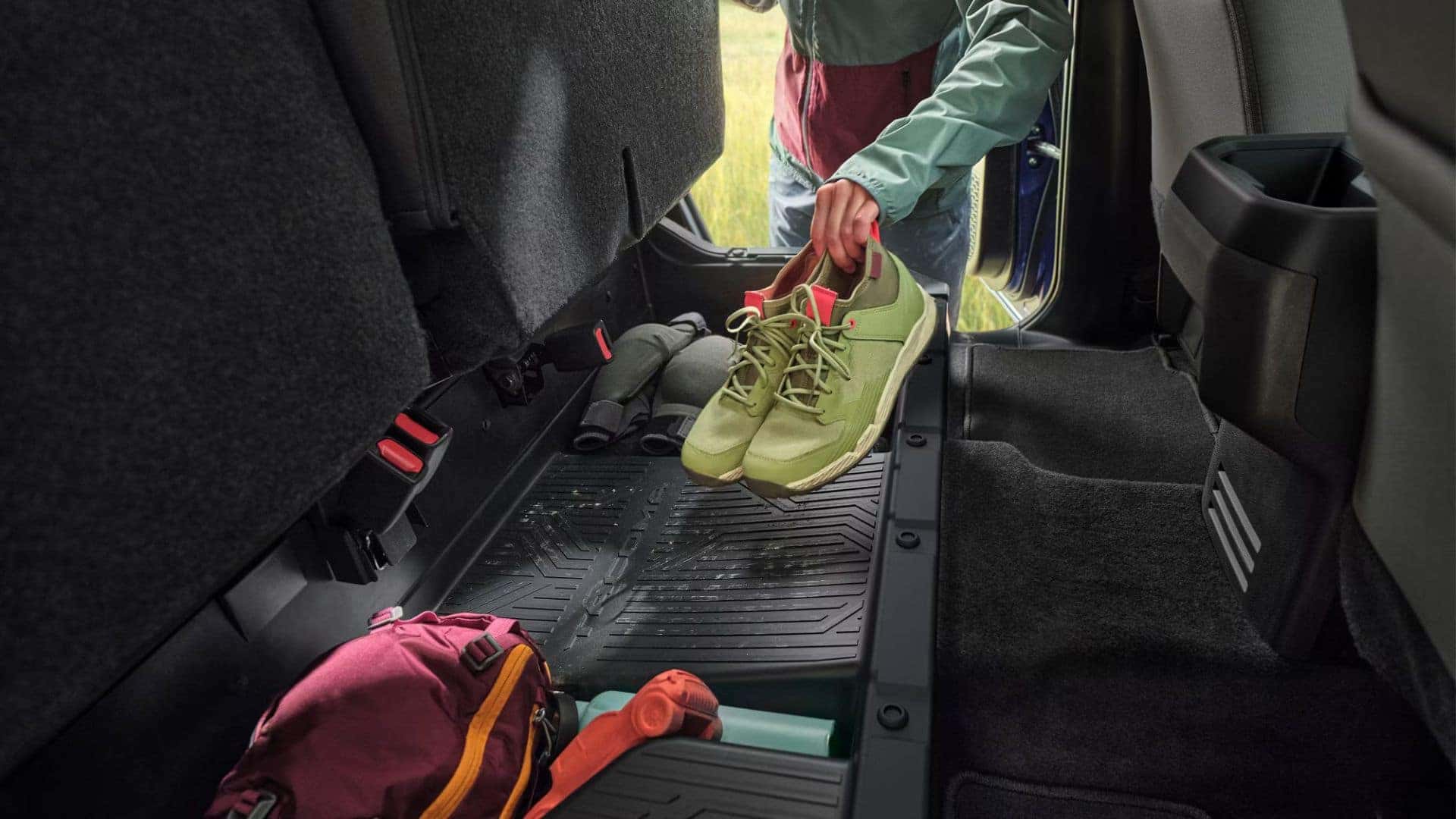 Interior storage of a Toyota Tacoma with under-seat storage space featuring shoes and camping gear.