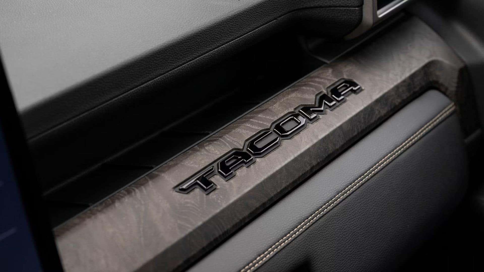 Interior dash detail featuring a 'Tacoma' logo embossed on a wood-accented trim piece.