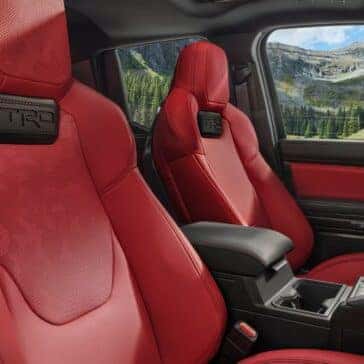 Interior view of a truck with TRD-branded red leather seats and a scenic mountain backdrop through the windows