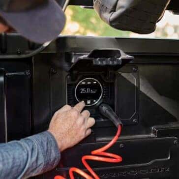 Close-up of an air compressor gauge inside a truck bed with a hand adjusting the pressure settings.