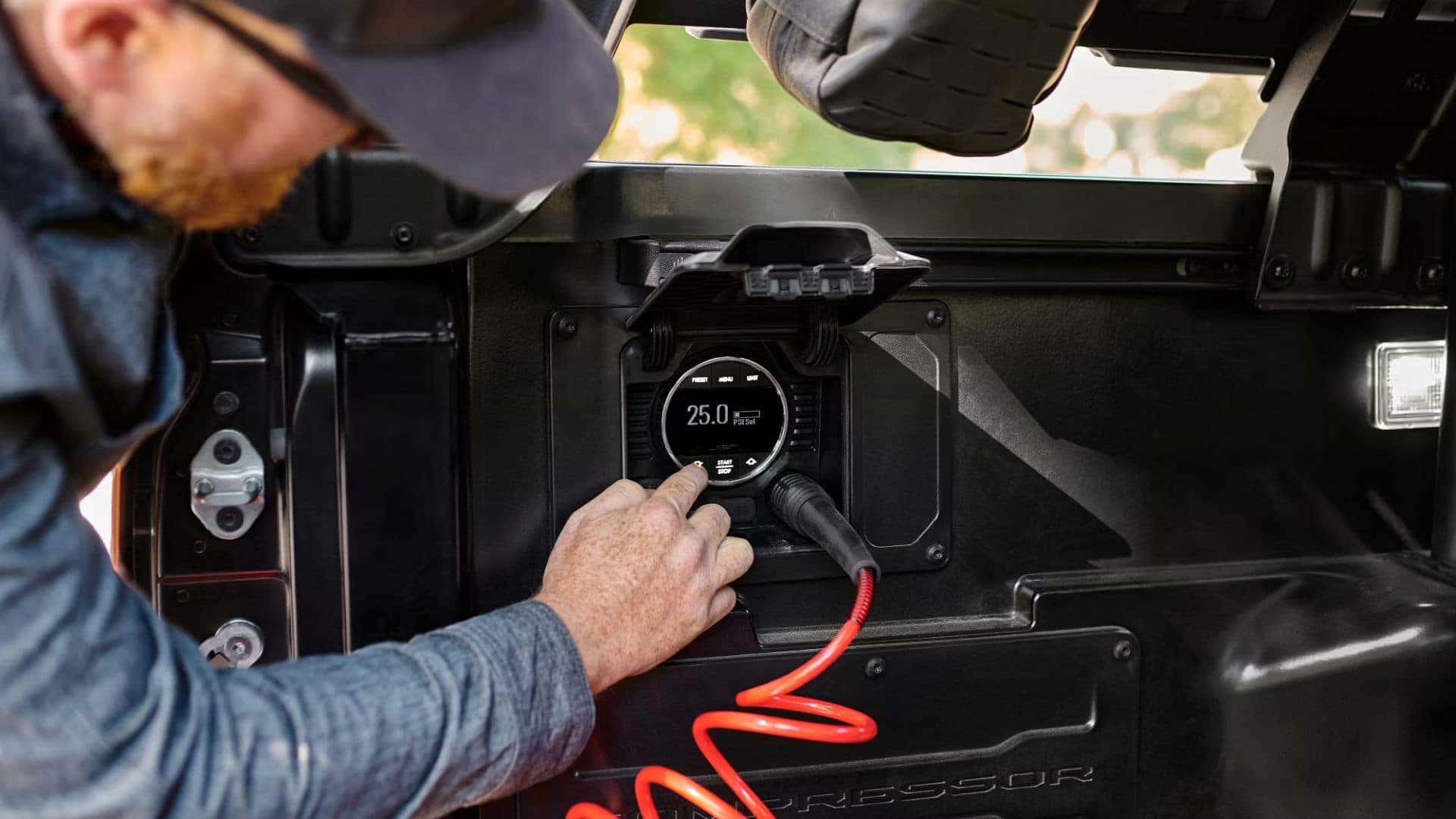 Close-up of an air compressor gauge inside a truck bed with a hand adjusting the pressure settings.