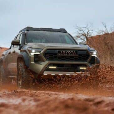 Toyota Tacoma splashing through muddy terrain, highlighting its off-road capability.