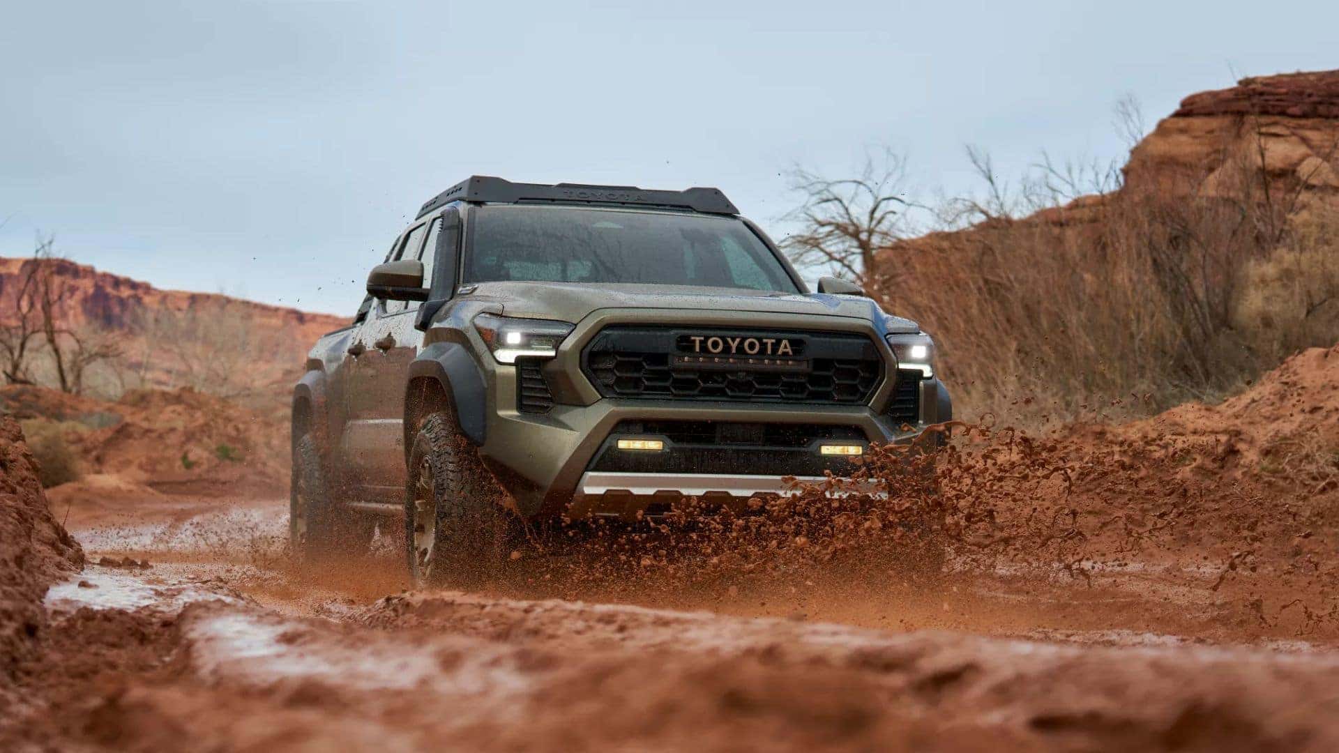 Toyota Tacoma splashing through muddy terrain, highlighting its off-road capability.