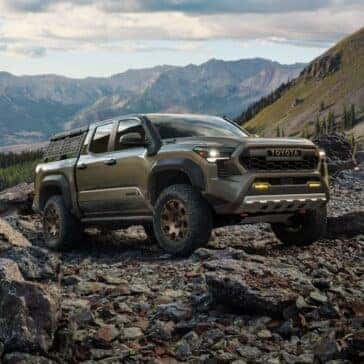 Toyota Tacoma parked on a rocky landscape with panoramic views of surrounding mountains and forests.