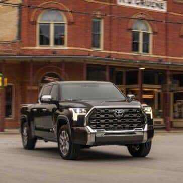 the front view of the 2025 1794 edition tundra in smoked mesquite exterior paint in front of an old building in a town setting