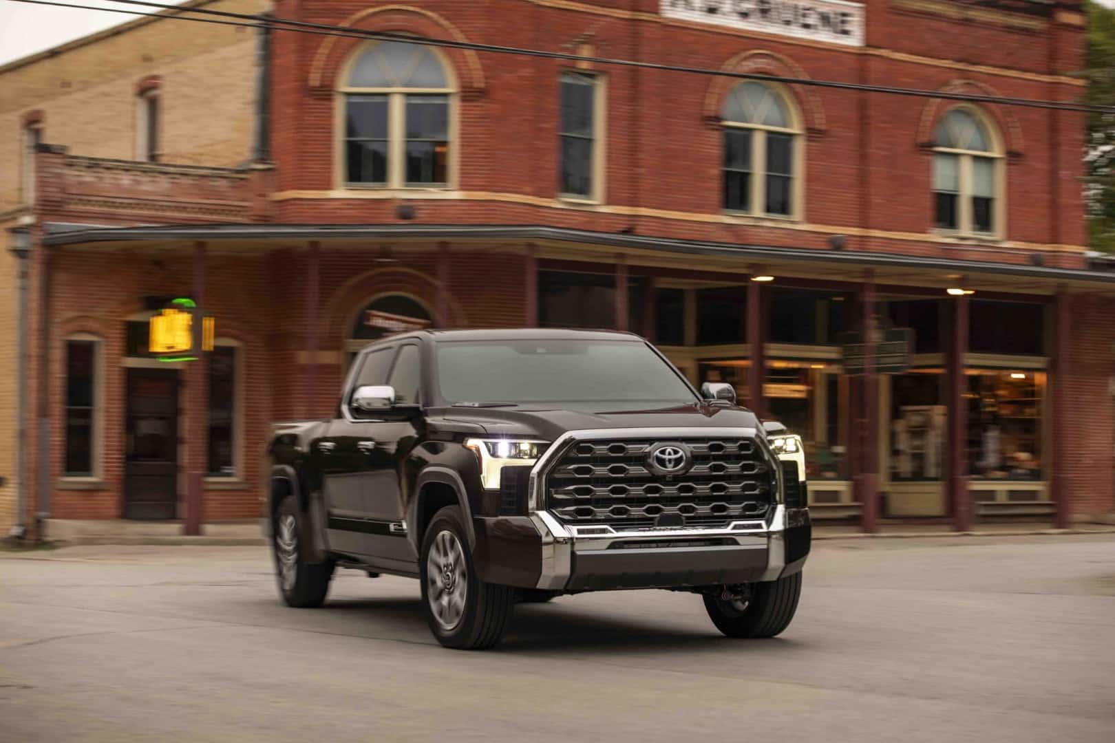 the front view of the 2025 1794 edition tundra in smoked mesquite exterior paint in front of an old building in a town setting