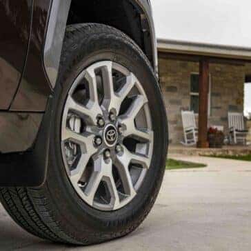 front passenger tire of a 2025 toyota tundra 1794 edition in smoked mesquite exterior paint with a house in the background