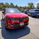 A red BMW iX3 on a scenic road.