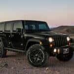 a black jeep in a desert at sunset