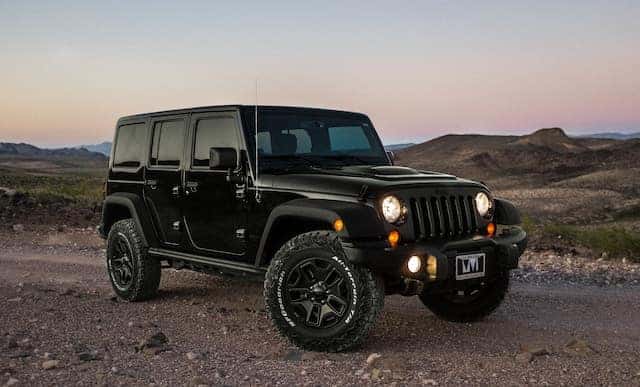 a black jeep in a desert at sunset