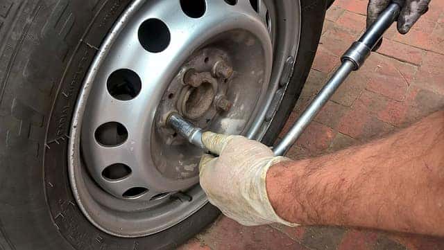 a closeup of a man with white gloves taking a tire off a car