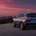 A pale blue 2022 Toyota Corolla Cross XLE is shown overlooking a city at sunset.