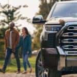 A couple is shown walking past a black 2022 Toyota Tundra 1794 CrewMax.