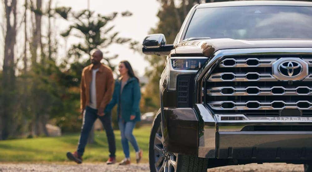 A couple is shown walking past a black 2022 Toyota Tundra 1794 CrewMax.