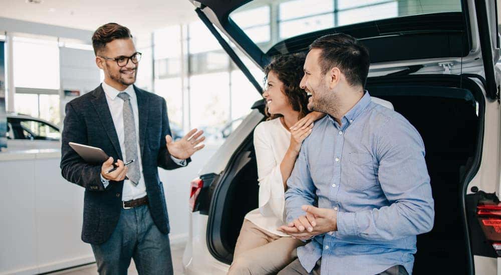 A salesman is shown speaking to customers at a ceritfied pre-owned Toyota dealership.