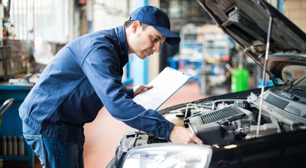 A mechanic is shown inspecting and engine at a certified pre-owned Toyota dealer.