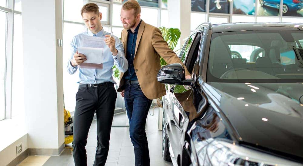 A salesperson is shown going over paperwork with a customer at a used car dealer near you.