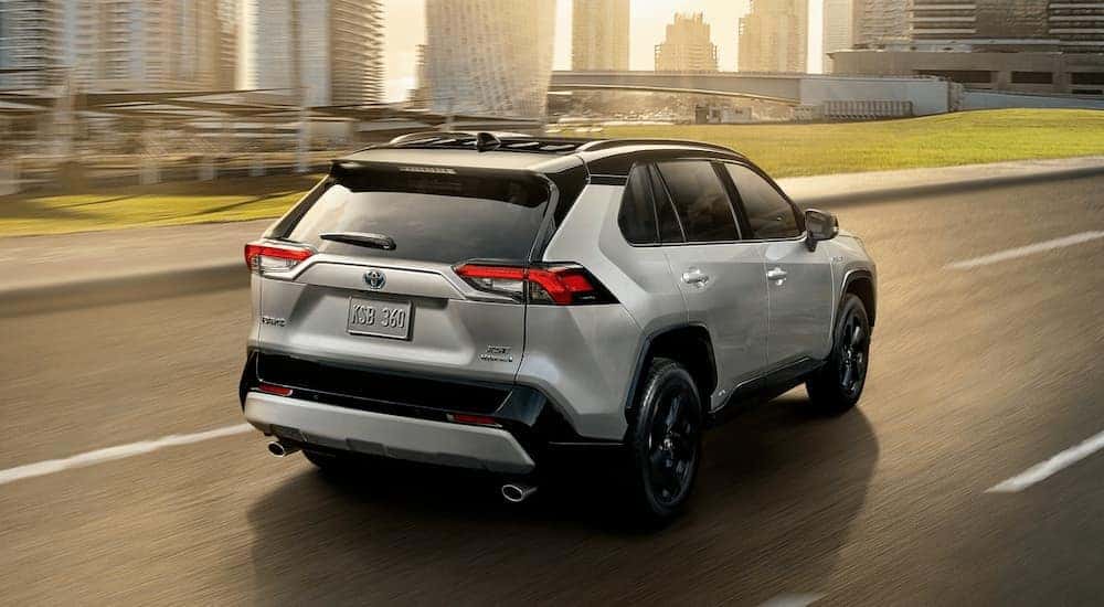 A silver 2019 Toyota Rav4 Hybrid is shown from the rear while driving down a city street.