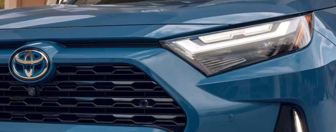 The headlight of a blue 2022 Toyota RAV4 is shown during a 2022 Toyota RAV4 vs 2022 Honda CR-V comparison.