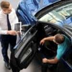 A person is shown getting out of a blue sedan.
