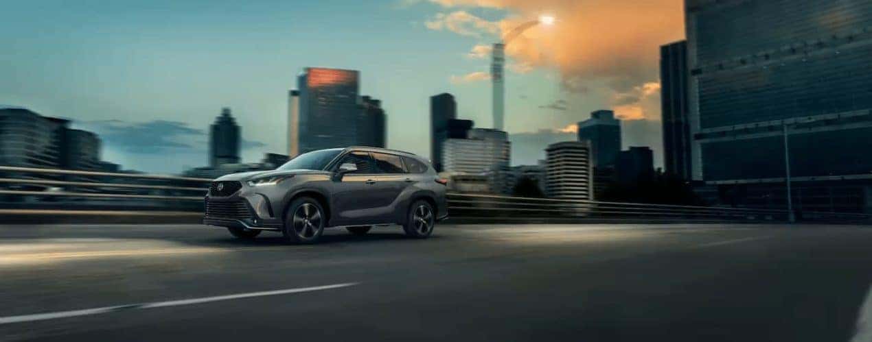 A grey 2022 Toyota Highlander is shown driving on a city highway.