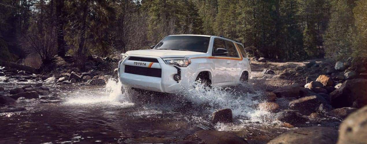 A white 2023 Toyota 4Runner 40th Anniversary Edition is shown driving through a river.