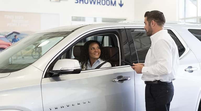 A girl sitting inside a dealership, looking at her computer.