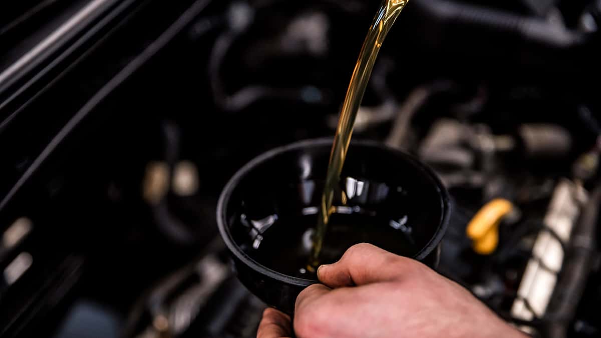 Close Up of Mechanic Adding Oil with a Funnel