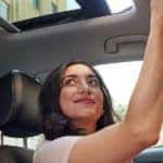 a woman grins inside a 2022 VW Jetta as she opens the sunroof