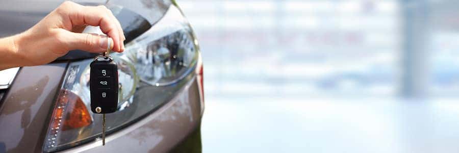 woman holding car keys in front of a car headlight