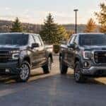 2026 Chevrolet Silverado 1500 and GMC Sierra 1500 parked side by side at a Wheelers Family Auto Group dealership in Central Wisconsin