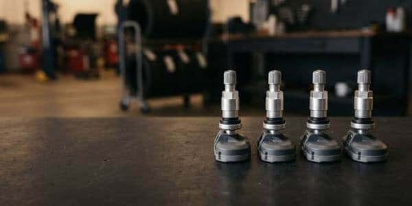 Four new TPMS tire pressure sensors on a service department bench